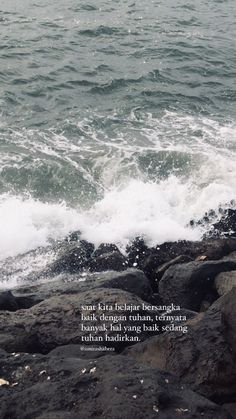 an ocean with waves crashing on the rocks and a quote written in english above it