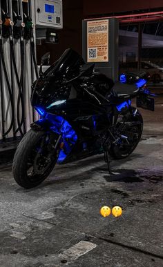 a black motorcycle parked in front of a gas station with blue lights on it's side