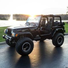 the jeep is parked on the side of the road by the water at sunset or sunrise