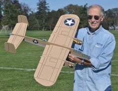 an older man is holding a cardboard airplane