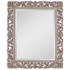 a mirror that is sitting on top of a white wall with an ornate design in the middle