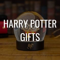 a harry potter snow globe with the words harry potter gifts in front of it on a wooden table