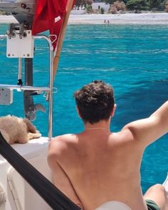 a man sitting on the back of a boat with his arm up in the air