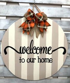 a welcome sign hanging on the side of a wooden wall with a bow and ribbon