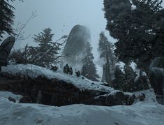 an image of a snowy mountain scene with rocks and trees in the foreground on a foggy day