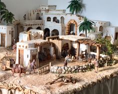 a model of a village with people and animals on the ground in front of it