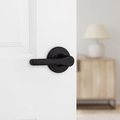 an open door with a black handle on it and a white lamp in the background