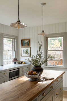 a wooden counter top in a kitchen next to two windows and a potted plant