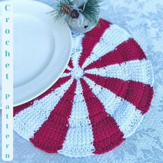 a red and white placemat with a pine cone on it, next to a plate