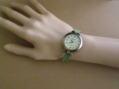 This is a round 1.25 inches diameter watch, made in alloy, aged bronze appearance, quartz with battery, analog. The wrist strap is made with synthetic green suede. The clasp is magnetic also made in alloy , aged bronze appearance. The strap comes in 5 measures: XS (for a 6 inches wrist), S (for a 6.25 inches wrist), M (for a 6.50 inches wrist), L (for a 6.75 inches wrist), XL (for a 7 inches wrist). NOTE: You can measure your wrist (no to tight, no too loose) with a thread, cord, strip of paper, Green Analog Watch As A Gift, Green Watch With Metal Dial As Gift, Green Analog Watch For Everyday Use, Everyday Green Quartz Watch, Green Watch With Metal Dial For Gift, Green Analog Outdoor Watch, Classic Adjustable Wrist Strap For Watches, Adjustable Green Analog Watch, Watch Minimalist