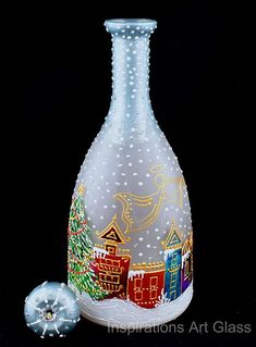 a glass bottle with a christmas scene painted on it and an ornament next to it