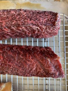 two raw steaks sitting on top of a metal rack