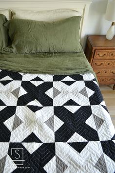 a black and white quilted bed with green pillows