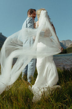 a bride and groom are walking by the water