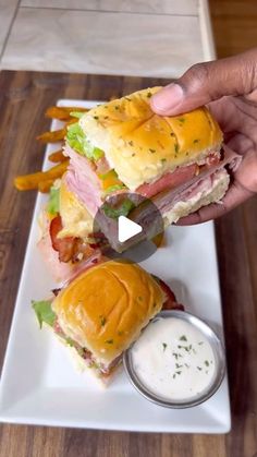 a person is holding up a sandwich on a white plate with mustard and ketchup