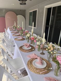 the table is set with pink and white flowers in vases, plates and napkins