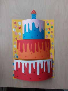 three birthday cakes are stacked on top of each other in front of a wooden wall