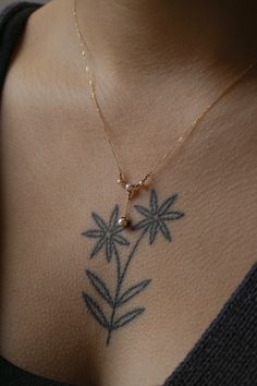 a woman's chest with a flower tattoo on her left shoulder and a pearl bead in the middle