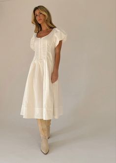 a woman in a white dress is posing for the camera