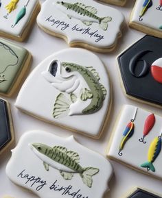 decorated cookies with fishing related items displayed on white table top, and happy birthday written in black lettering