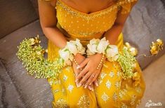 a woman in a yellow dress with flowers around her waist and hands on her knees