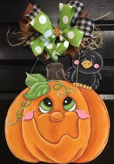 an orange pumpkin with two black birds on it and a green polka dot bow hanging from the front door