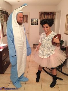 a man and woman dressed up as shark and girl in pink tutu skirt standing next to each other