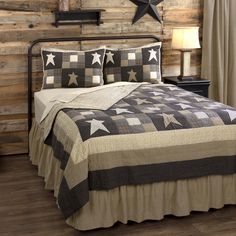 a bed with a black and white quilt on top of it next to a wooden wall