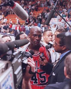 the basketball player is surrounded by reporters and microphones