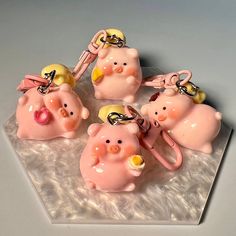 five pink pig keychains with gold bells on top of a marble slabd surface