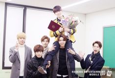 group of young men standing in front of a whiteboard with flowers on it's shoulders