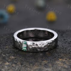 a silver ring with a green stone in the middle on top of a granite surface