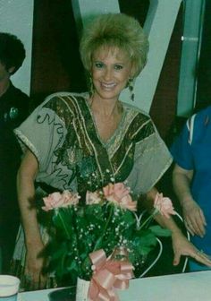 an older woman sitting at a table with flowers