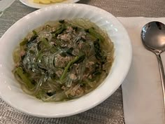 a white bowl filled with food on top of a table next to a spoon and fork