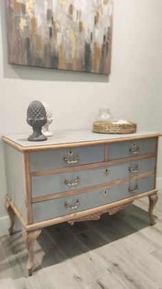 an old dresser is painted blue and gold with silver hardware on the top, along with a basket