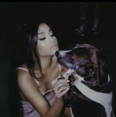 a woman is petting a dog with her nose close to the camera while sitting down