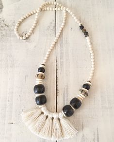 a white and black beaded necklace with tassels on a wooden surface,