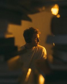 a man with earphones standing in front of a stack of books and looking off into the distance