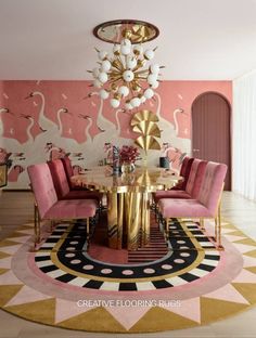 a pink and gold dining room with flamingos on the wall, chandelier and chairs