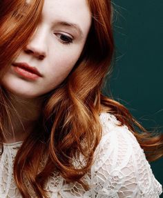 a woman with long red hair is looking at the camera and has her eyes closed