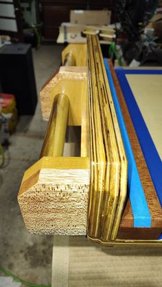 a bench made out of wood with blue tape on the edge and another piece of wood behind it