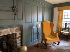 a yellow chair sitting next to a fireplace in a bedroom