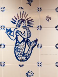 a blue and white tile wall with an image of a mermaid holding a starfish