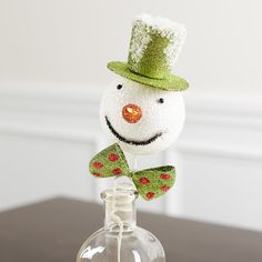 a snowman in a green top hat holding a candy cane