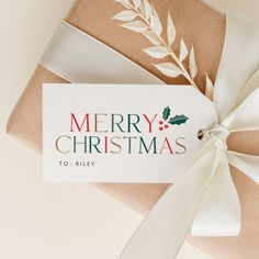 a gift wrapped in brown paper with a white ribbon and merry christmas tag on it