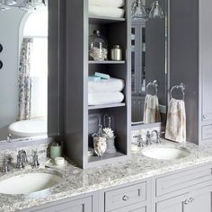 a bathroom with double sinks and gray cabinets