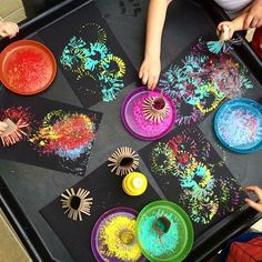 children are making art with paper plates and colored paint on a tray in front of them