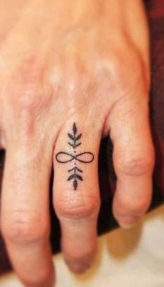 a woman's hand with a small tattoo on the middle finger and an arrow