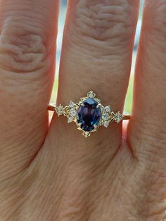 a woman's hand with a ring on it that has a blue stone in the middle