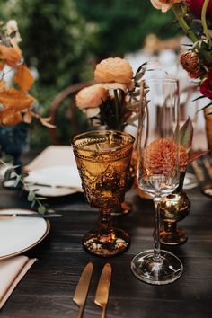 the table is set with flowers and goldware